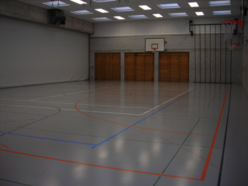 Die alte Turnhalle mit grauem Fussboden, Ton in Ton mit der gemauerten Wand.